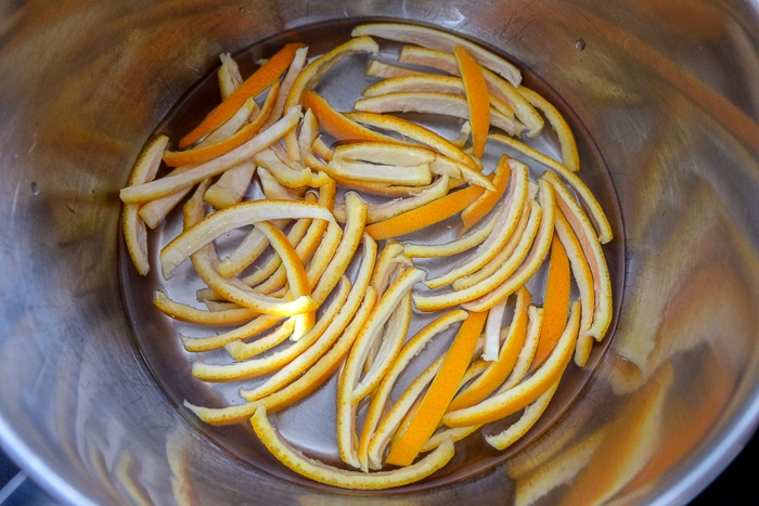sliced orange peels placed in metal pot with water