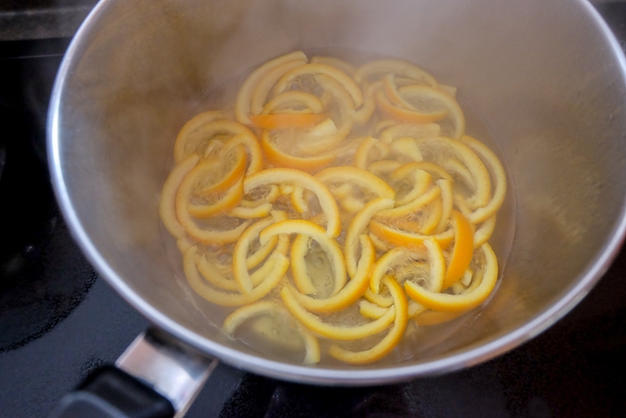 sliced orange peels boiling in pot on stove