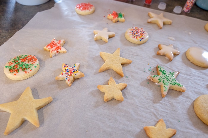butter cookies on parchment paper decorated with icing and sprinkles
