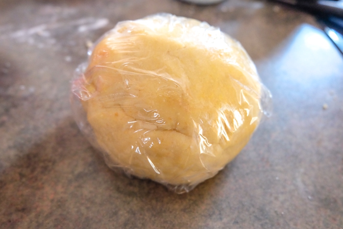 ball of german butter cookie dough in cling film on kitchen counter