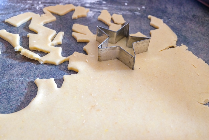 star cookie cutter cutting cookies out of flat dough on counter