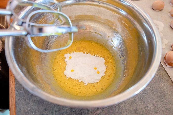 icing sugar with egg yolks in mixing bowl with mixer beside