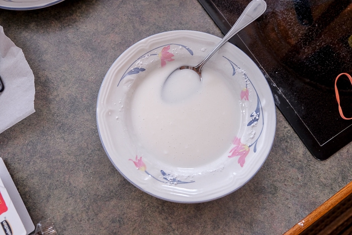 white bowl of white icing with spoon inside