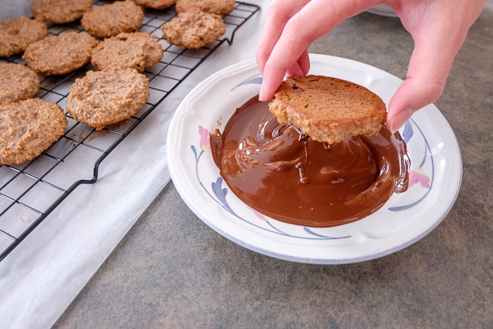 dipping german gingerbread cookie in chocolate in bowl on counter