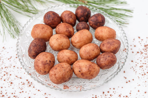 brown marzipan potatoes on clear decorative plate with christmas branch behind