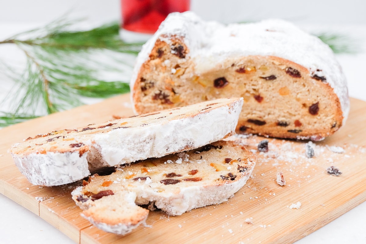 german stollen bread sliced on wooden cutting board with red drink behind
