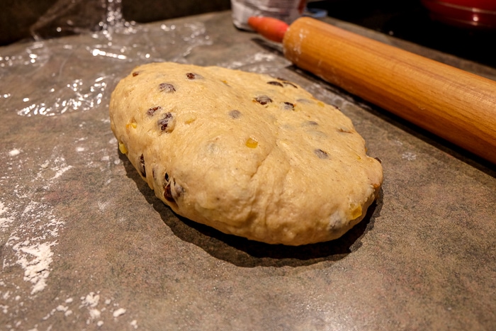 loaf of raw stollen dough with flattened side beside rolling pin