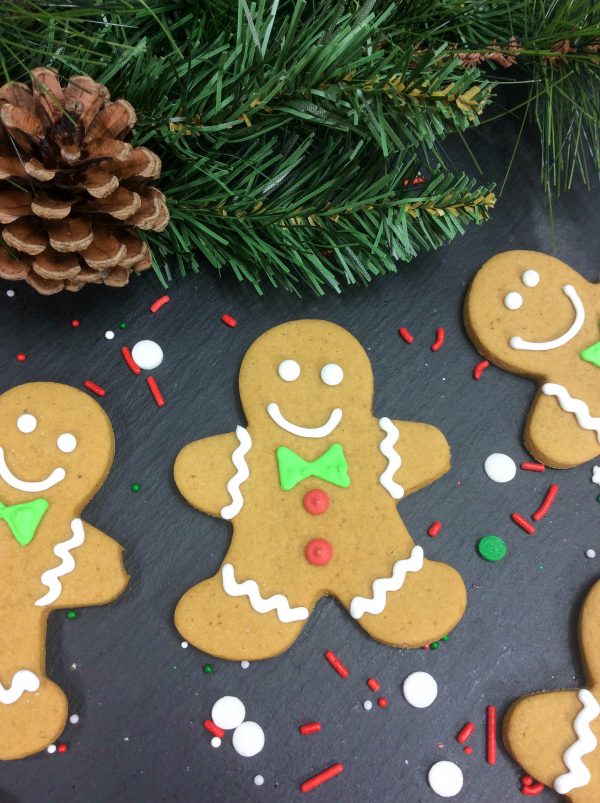 decorated gingerbread men with sprinkles as decoration next to them.