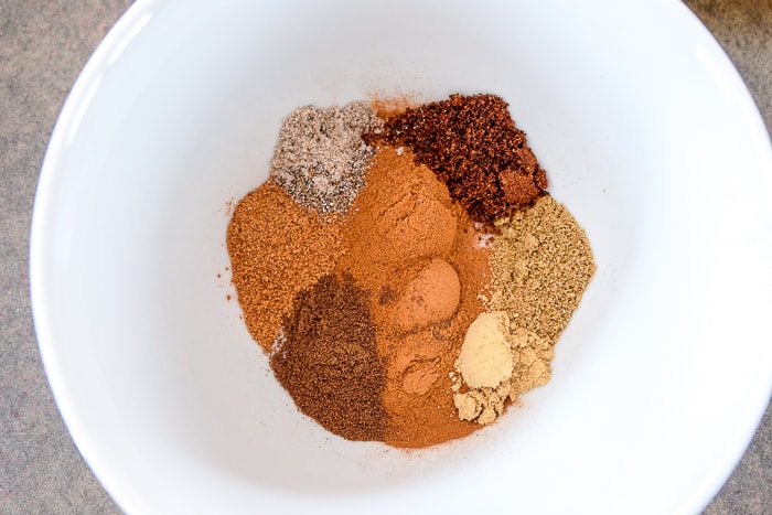 various ground spices for homemade gingerbread spice in white bowl