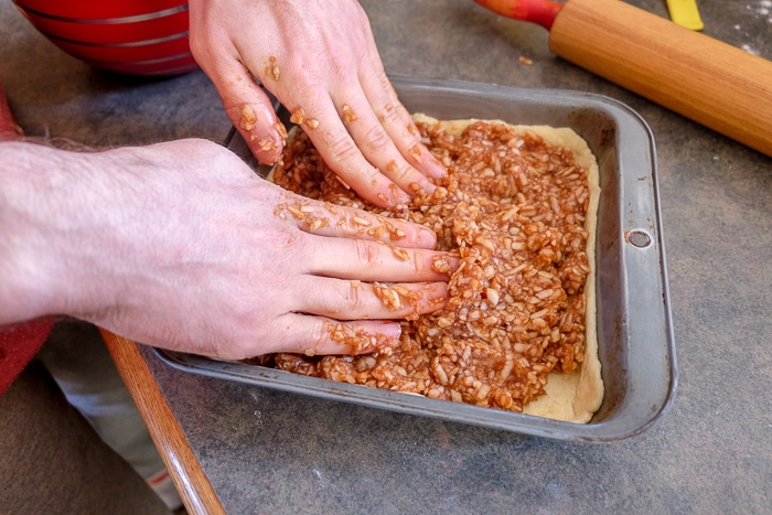 pressing hungarian apple pie filling into dough pan