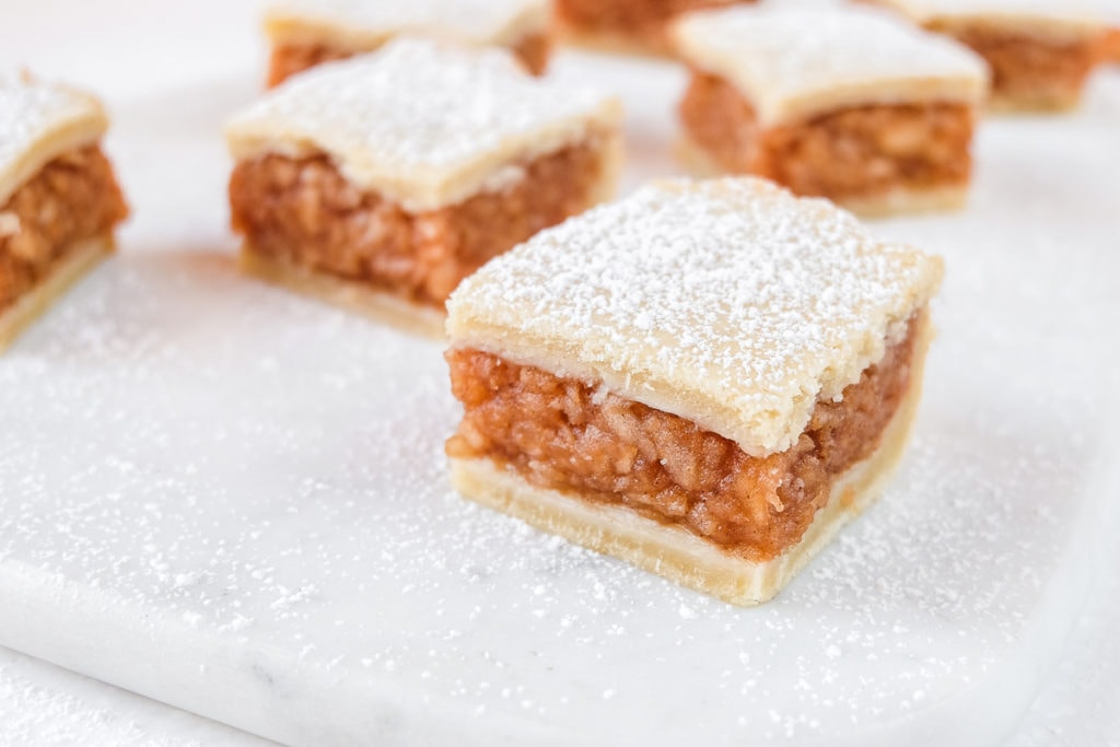 hungarian apple pie squares with powdered sugar on white marble