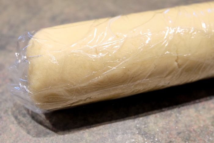 roll of marzipan wrapped in cling film on countertop