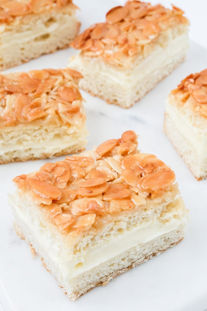 slices of almond covered bee sting cake on white marble counter