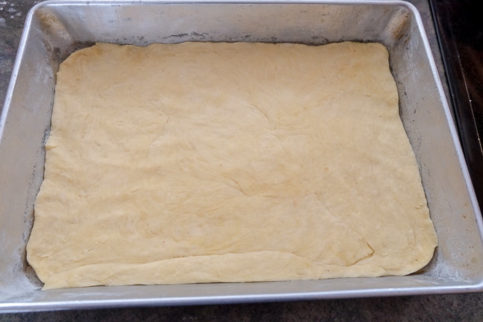 raw Bienenstich cake dough base in silver baking tray