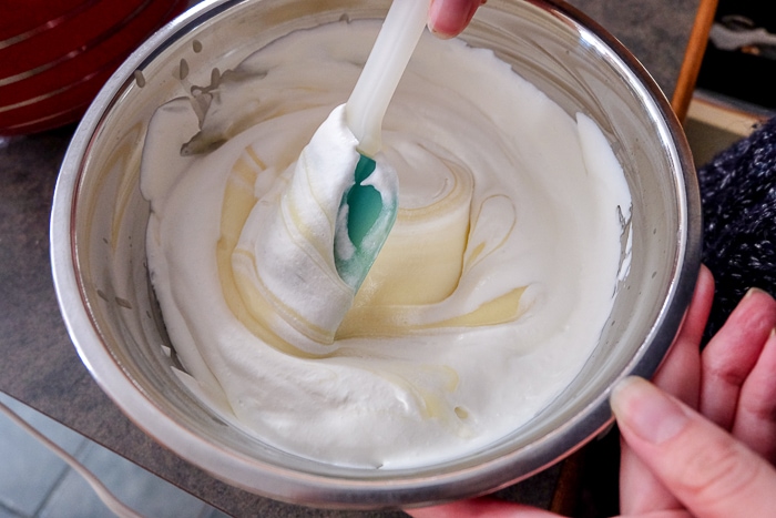 folding whipping cream into vanilla pudding with spatula in bowl
