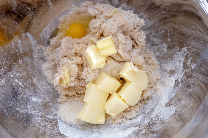 butter and egg with dough in silver mixing bowl