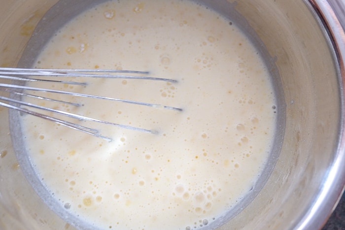 milk with metal whisk in metallic mixing bowl