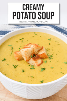 photo of creamy potato soup in white bowl with croutons on wooden board and text overlay saying creamy potato soup