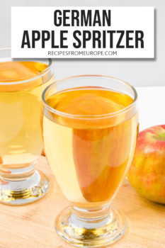 Photo of golden liquid in two glasses with whole apple in background and text overlay saying German apple spritzer