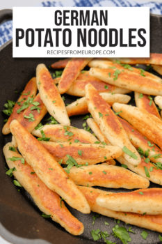 German potato noodles in black cast iron pan with cut up parsley on top and text overlay saying German potato noodles