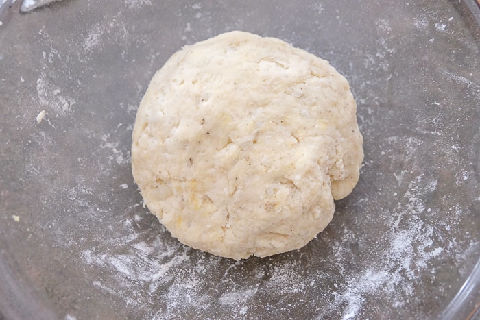 ball of potato noodle dough on counter top with flour