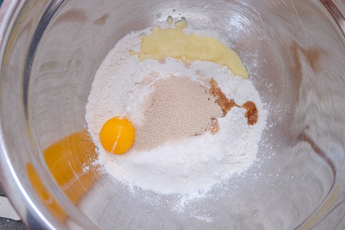 silver mixing bowl of egg flour and yeast