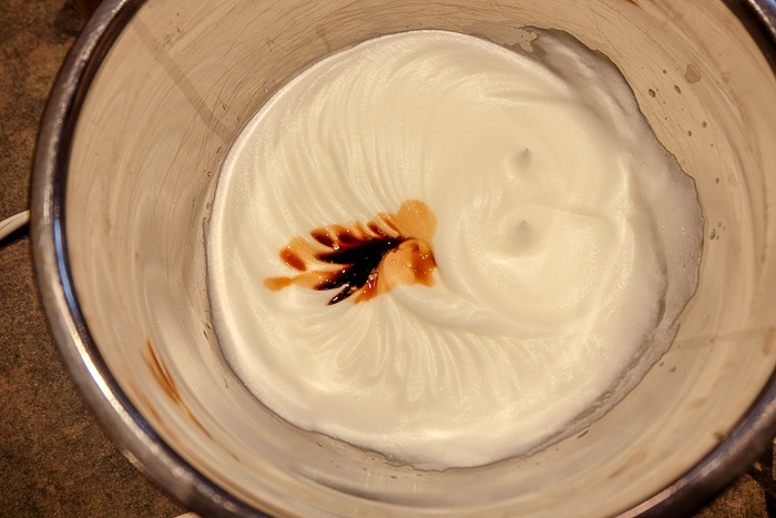 vanilla extract in stiff egg whites in metallic bowl