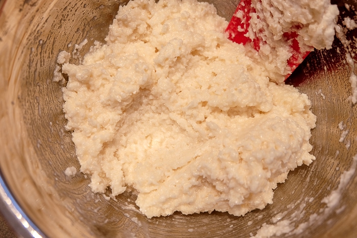 coconut macaroon batter in metallic bowl with red spatula
