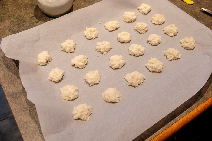 raw coconut macaroons in rows on baking sheet with parchment paper