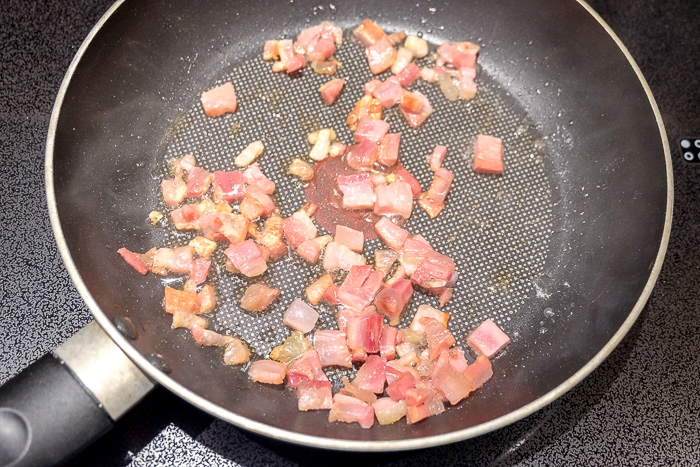 pancetta bacon frying in frying pan on stove