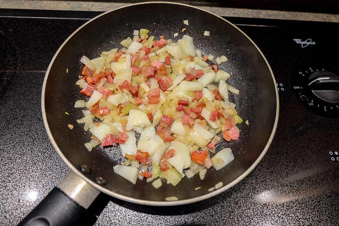 pancetta bacon and onions frying in black frying pan