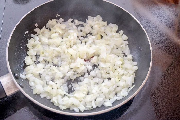 chopped onions frying in black frying pan on stove