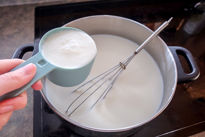 metal pot with whisk with measuring cup of buttermilk above it