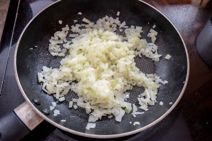chopped onions in black frying pan on stove