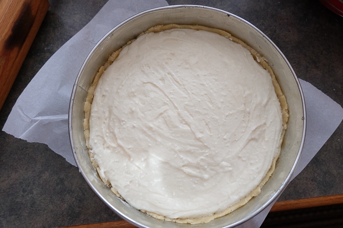raw german cheesecake filling in crust in round silver pan on counter