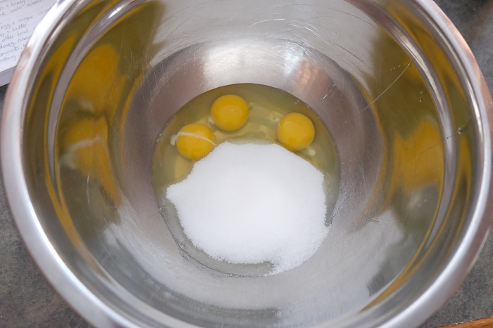 three eggs in metallic mixing bowl with sugar