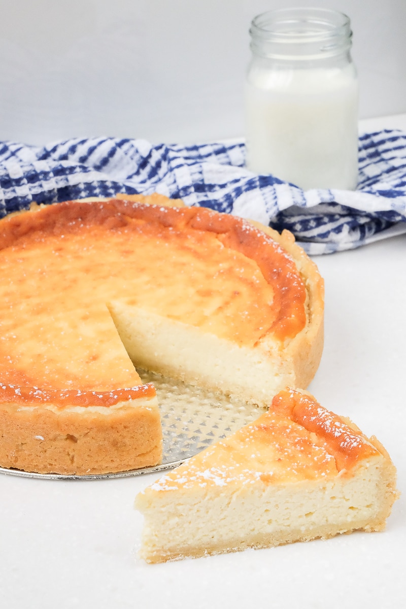 golden german cheesecake with slice cut and milk behind