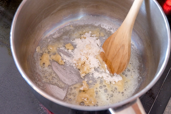 flour in melted butter stirred by wooden spoon in pot
