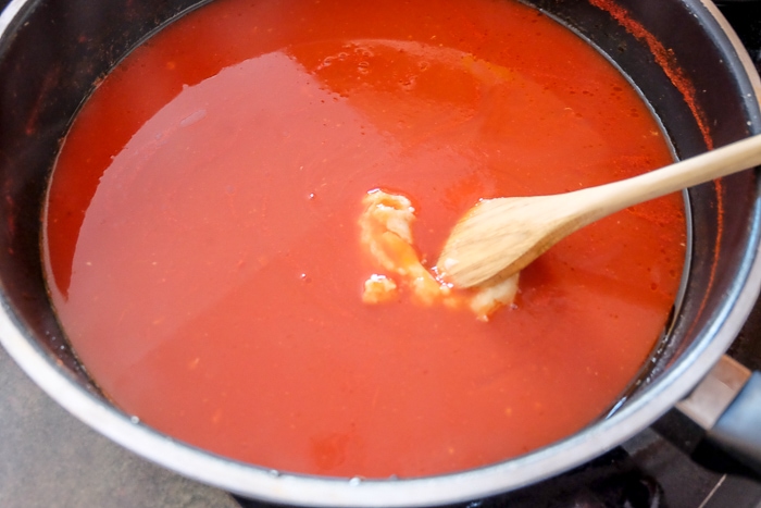 roux in tomato sauce in sauce pan with wooden spoon