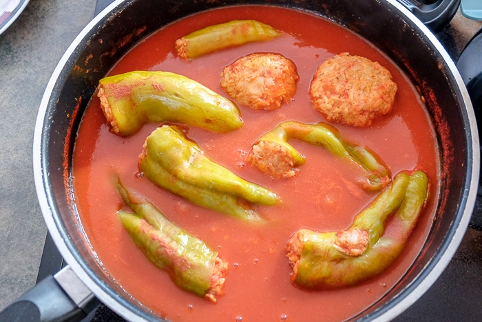 hungarian stuffed peppers in red tomato sauce in pan on stove