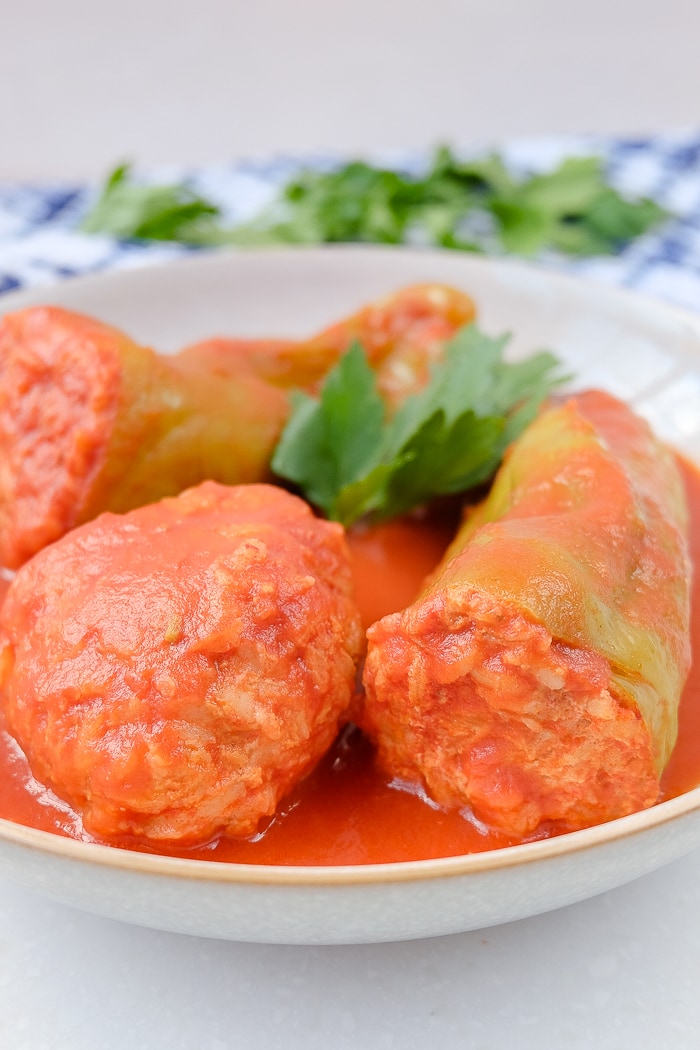 hungarian stuffed peppers in red sauce and meatball in bowl with parsley