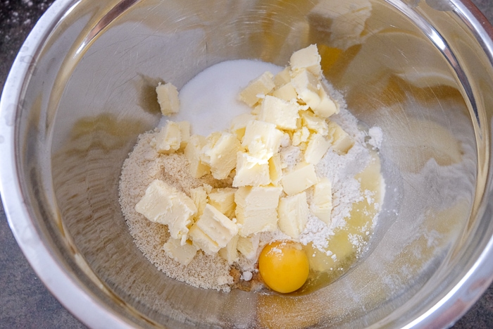 butter and egg with linzer cookie ingredients in metallic mixing bowl