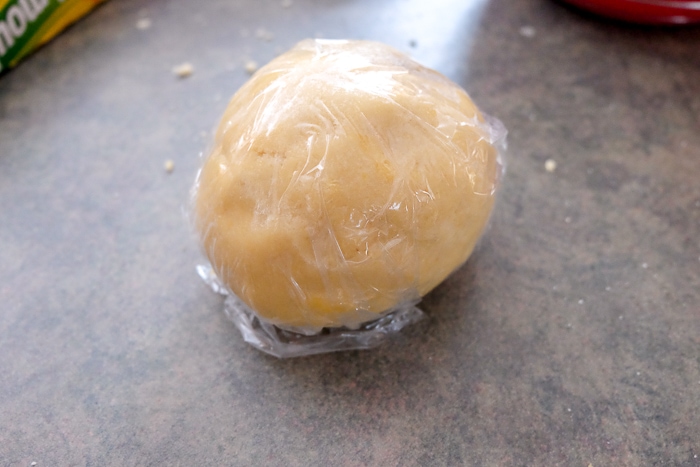 ball of linzer cookie dough in cling wrap on counter