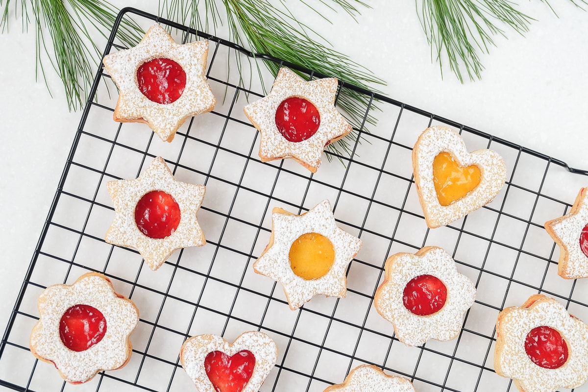 colorful linzer cookies on black cookie cooling tray