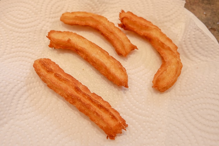 cooked spanish churros on paper towel on plate