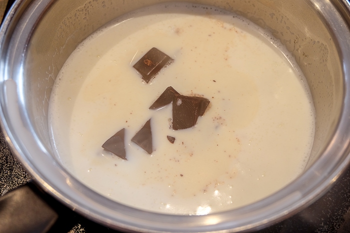 chunks of chocolate melting in milk in silver pot