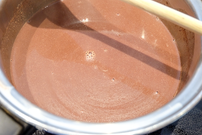 spanish hot chocolate bubbling in silver pot on stovetop
