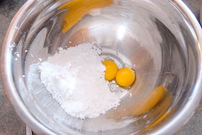 egg yolks and icing sugar in silver mixing bowl