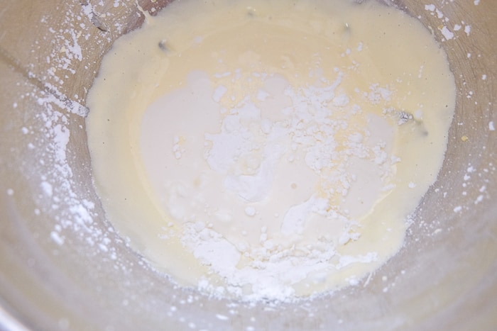 corn starch added to wet ingredients in silver mixing bowl