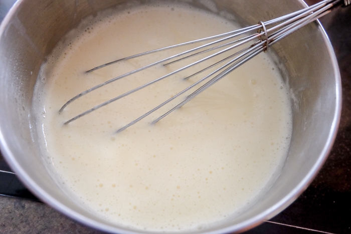 pot of hot vanilla sauce with whisk inside on stove